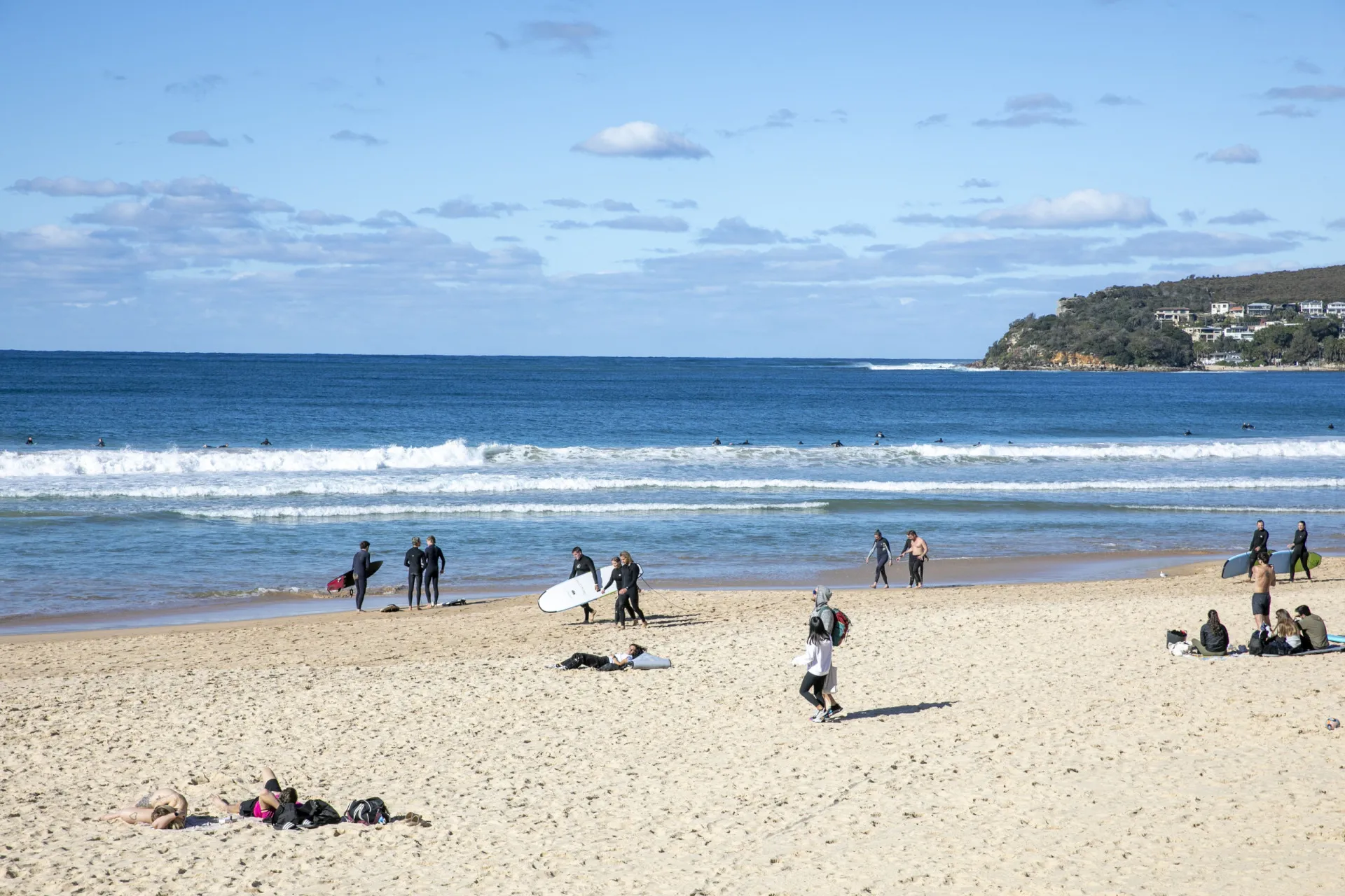 Surfistas aproveitando as ondas em Manly Beach, Sydney, com a cidade ao fundo.