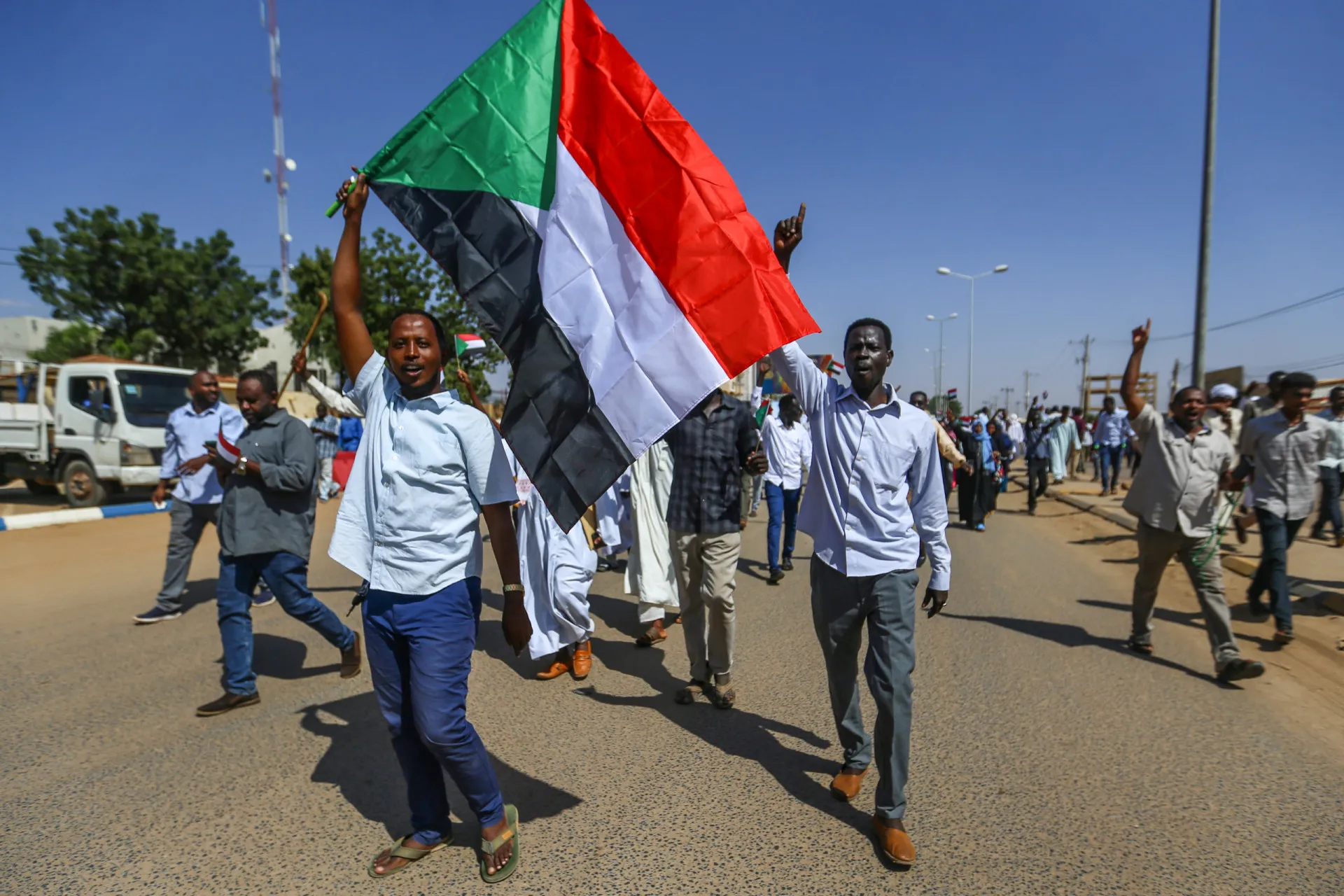 Um líder comunitário falando com um grupo de pessoas em uma aldeia sudanesa.