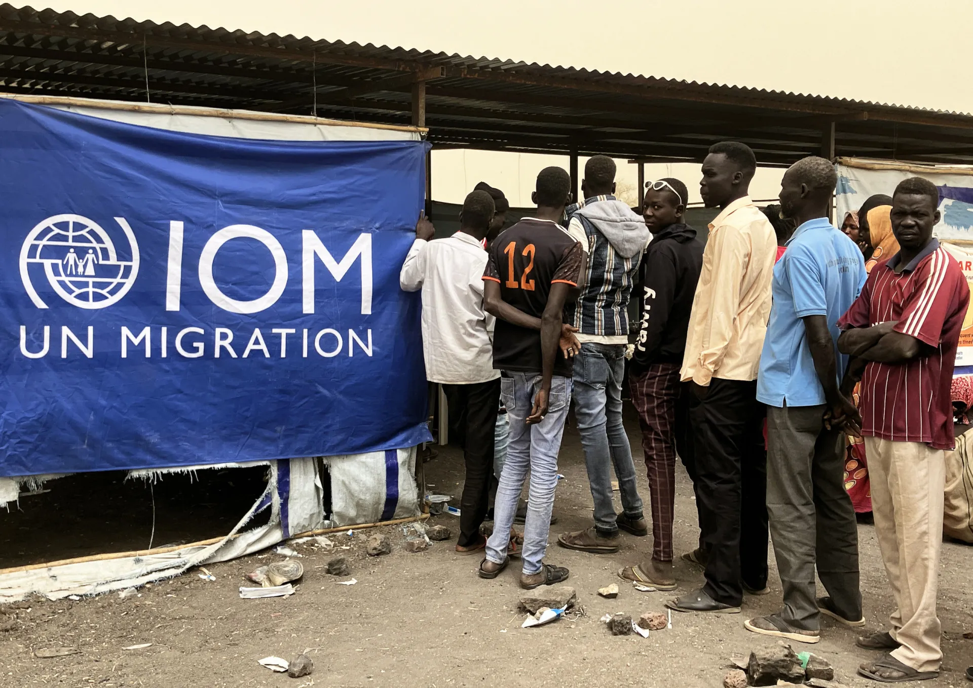 Jovens sudaneses reunidos em um círculo de discussão, olhando para um laptop.