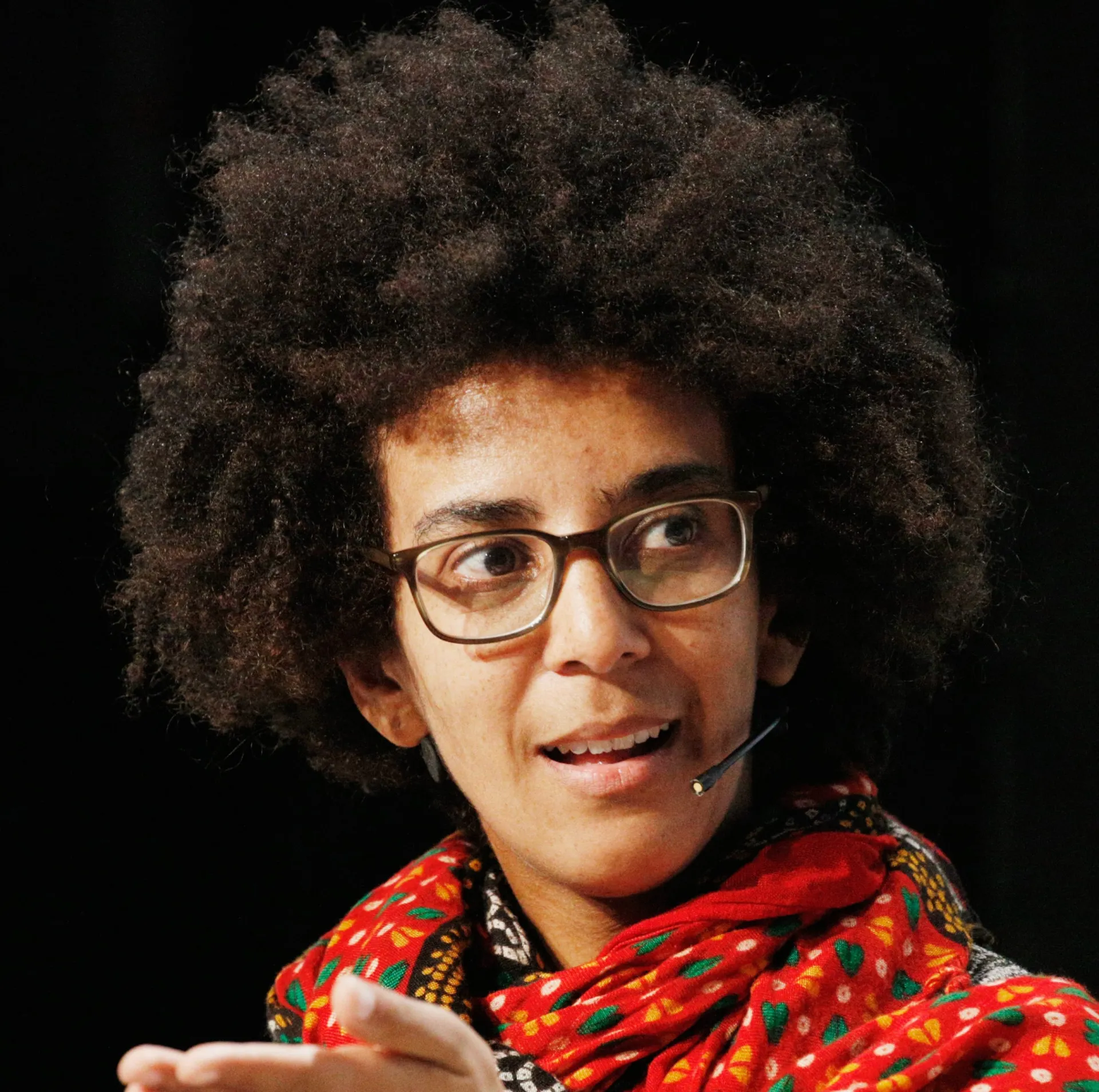 Timnit Gebru, uma mulher negra com óculos, falando em um microfone.