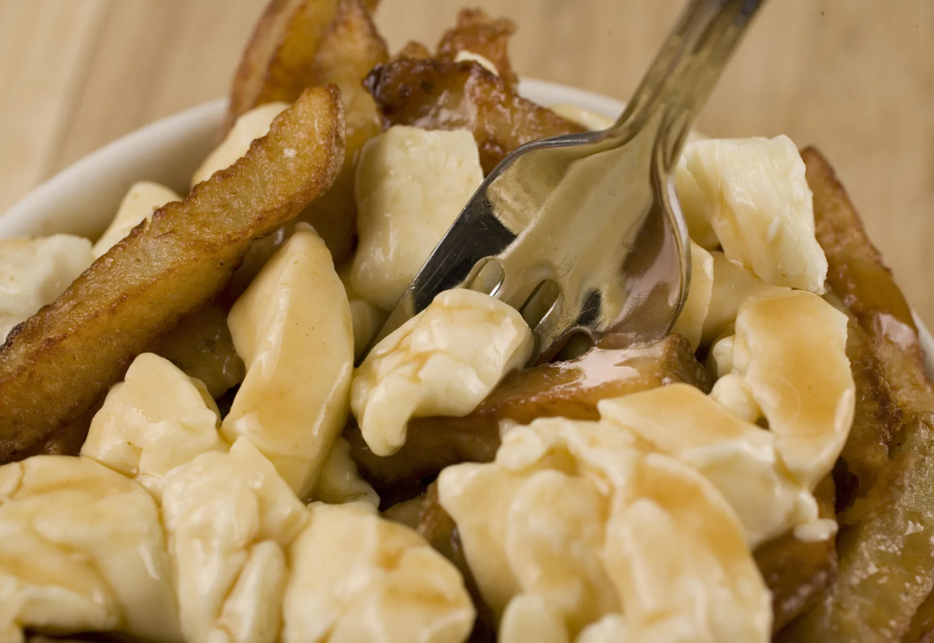Prato de poutine, com batatas fritas, queijo coalho e molho gravy.