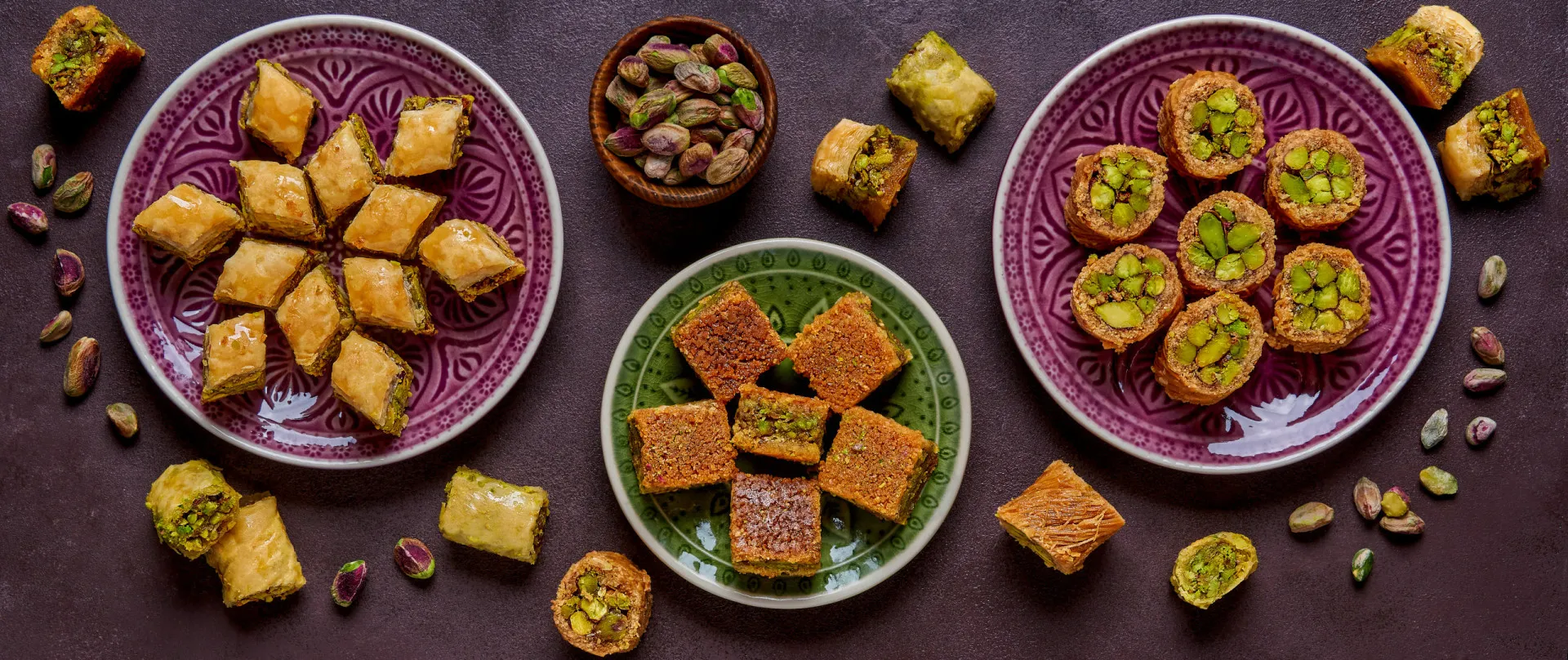 Prato de kebab turco com acompanhamentos e um pedaço de baklava ao lado.