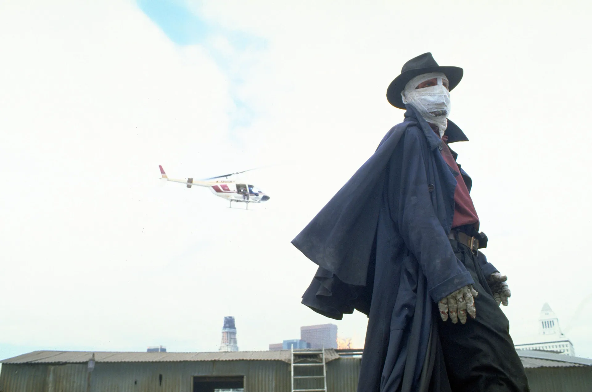 Darkman, com o rosto coberto por ataduras, revelando um olhar de fúria e dor.