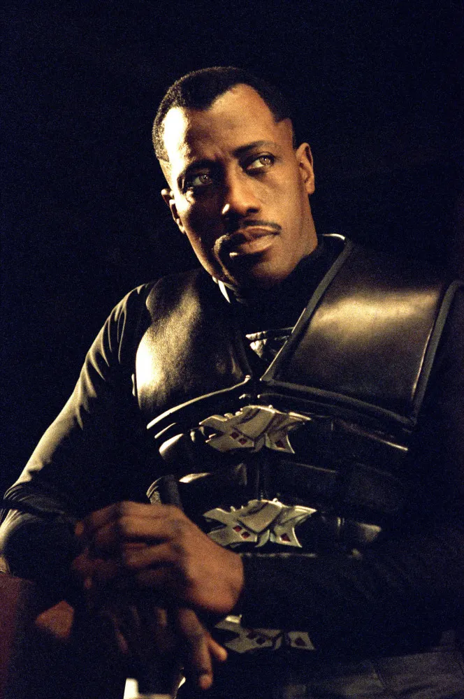Blade, o Daywalker, com seu sobretudo de couro preto e óculos escuros, segurando sua katana.