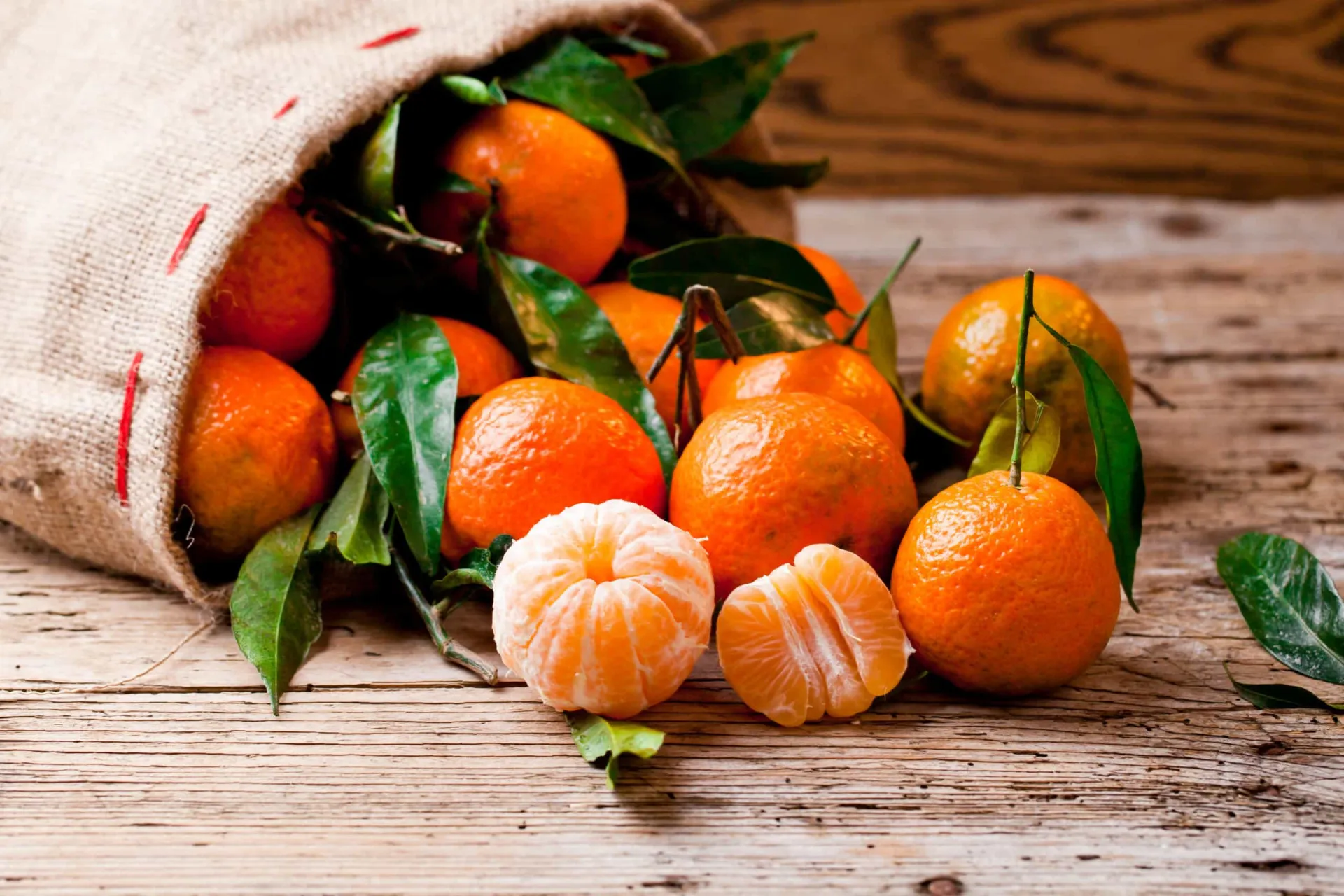 Tangerinas descascadas ao lado de uma inteira, mostrando seus gomos suculentos.