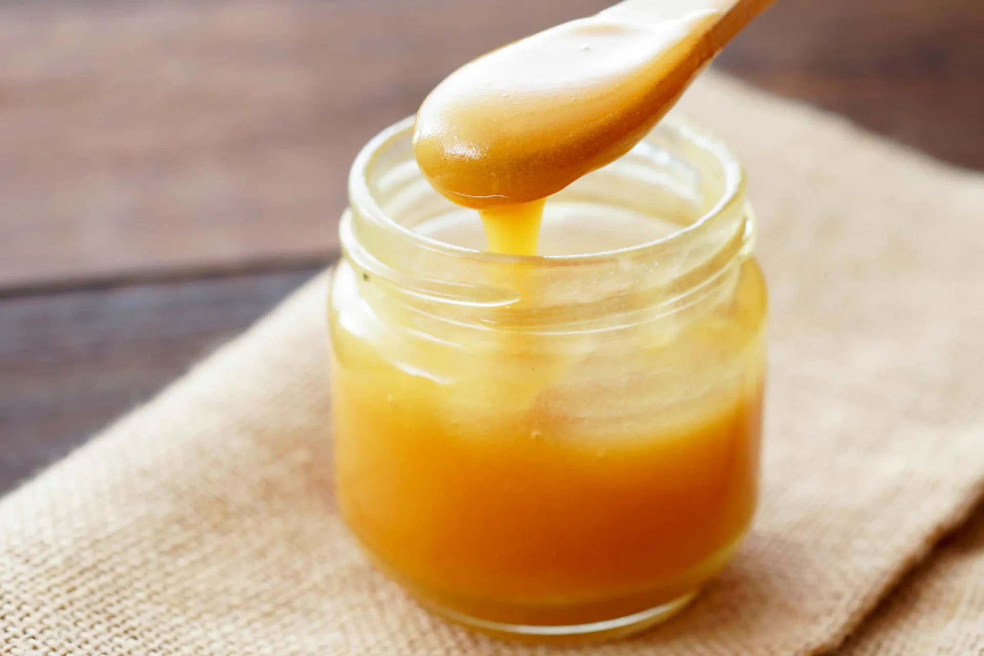 Pote de mel de Manuka com um favo de mel ao lado.