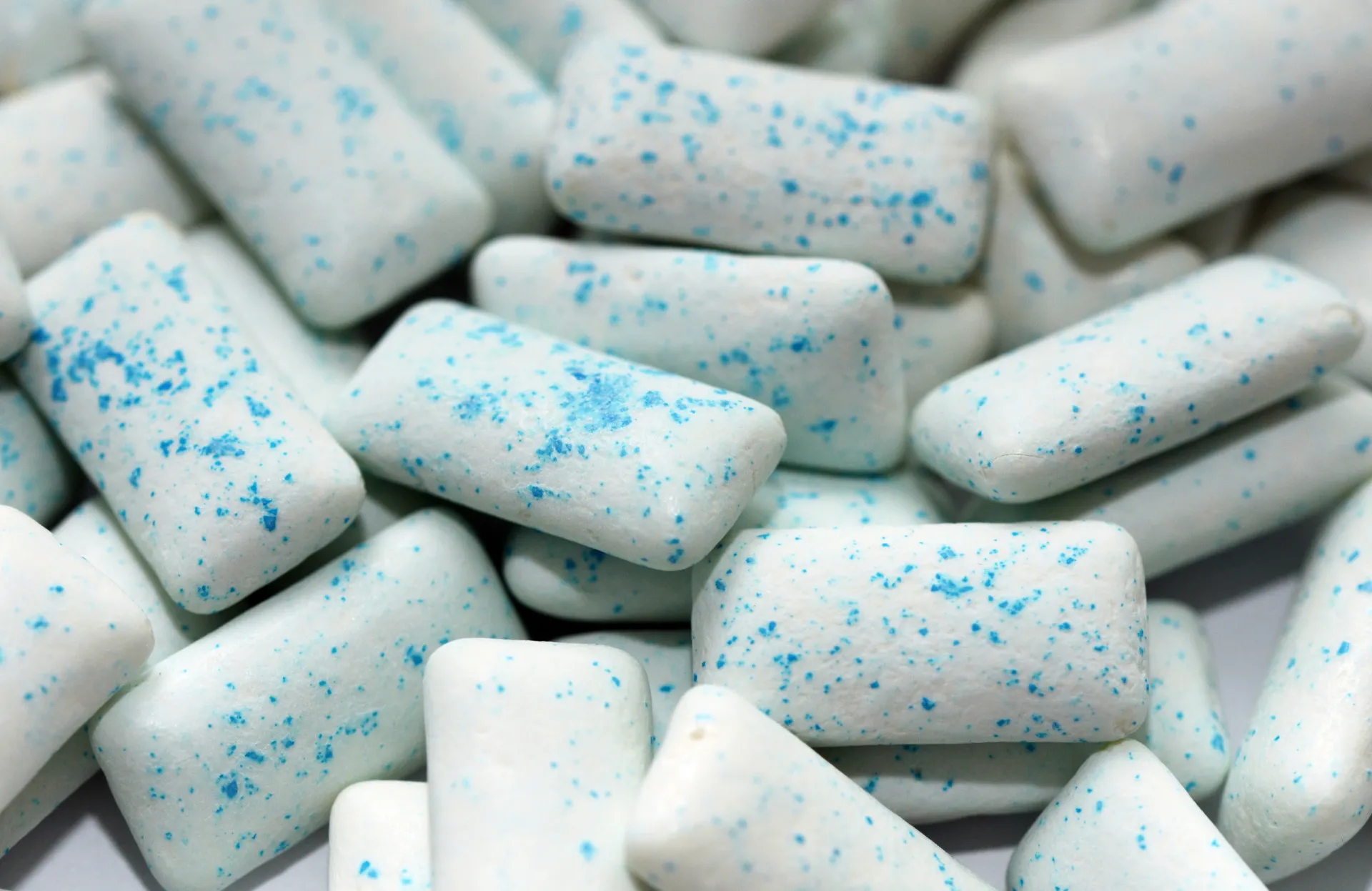 Pessoa mascando chiclete, focando no aumento da produção de saliva.