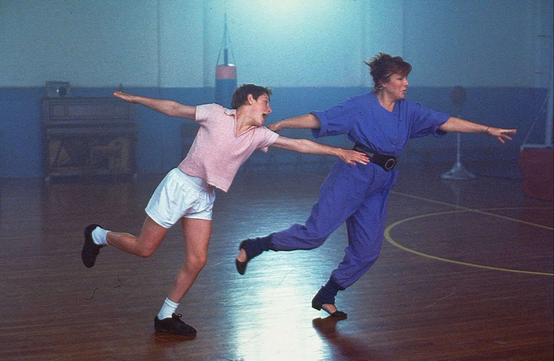 Jamie Bell como Billy Elliot, saltando no ar em um movimento de balé expressivo.