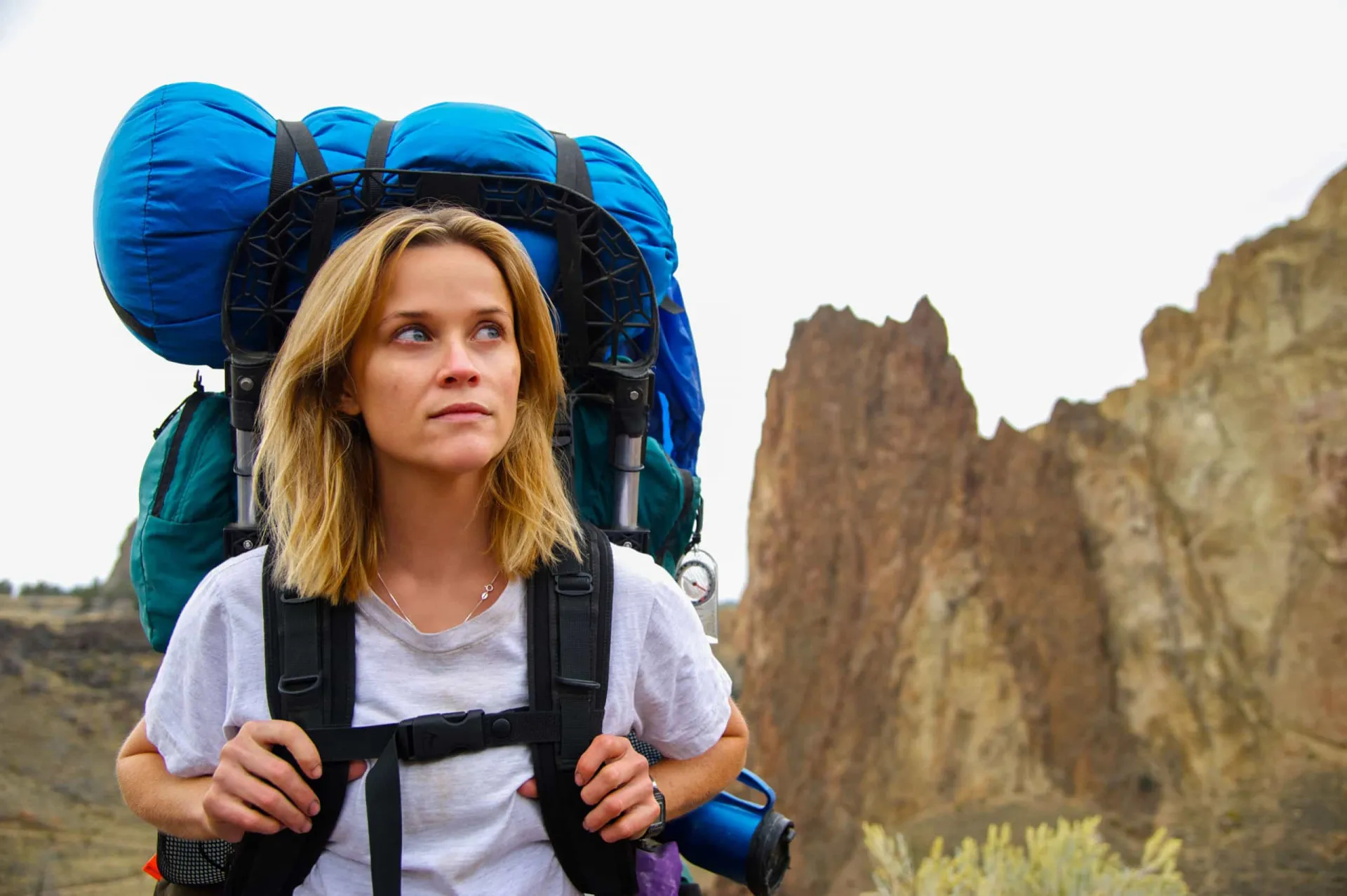 Reese Witherspoon como Cheryl Strayed no filme 'Livre', carregando uma mochila enorme durante sua caminhada.