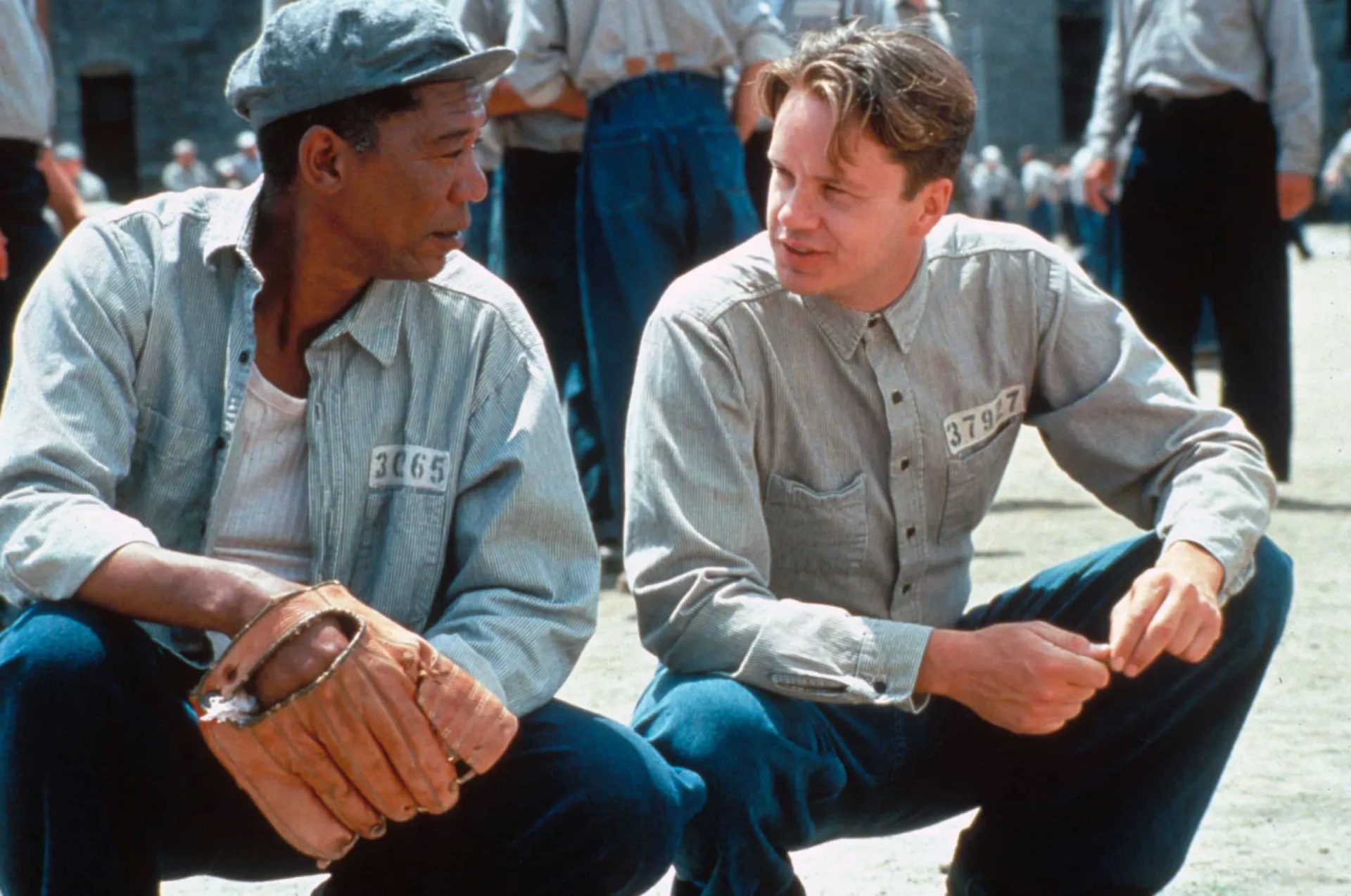 Tim Robbins e Morgan Freeman como Andy e Red no filme 'Um Sonho de Liberdade', conversando no pátio da prisão.