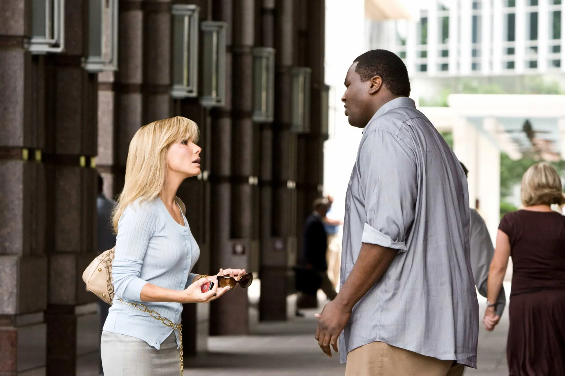 Sandra Bullock como Leigh Anne Tuohy, caminhando ao lado de Quinton Aaron como Michael Oher em um campo de futebol americano.