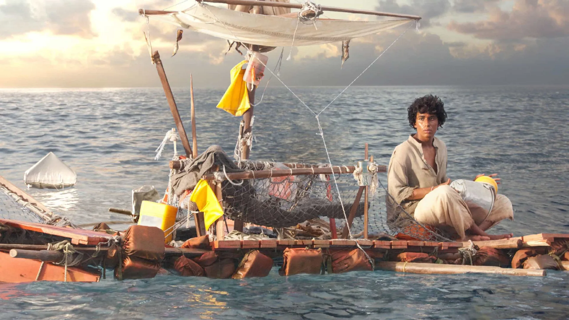 O jovem Pi em um bote salva-vidas no meio do oceano, ao lado de um tigre de Bengala.