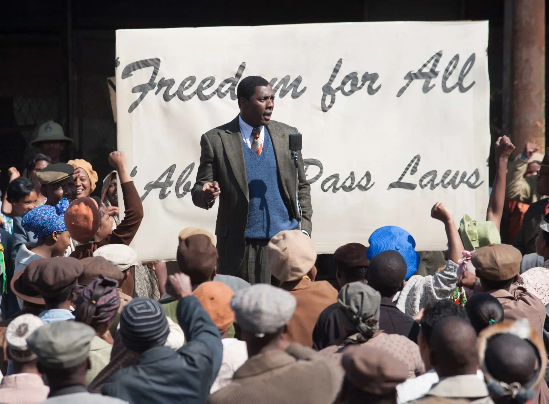 Idris Elba como Nelson Mandela, com o punho erguido em um gesto de resistência.