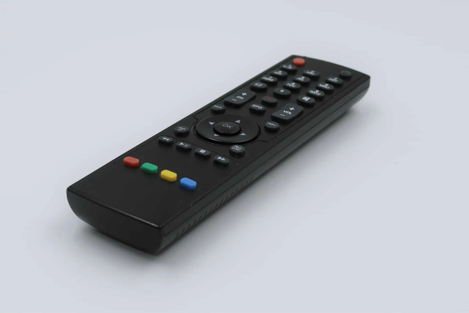 Mão segurando um controle remoto de TV, um item frequentemente esquecido na hora da limpeza.