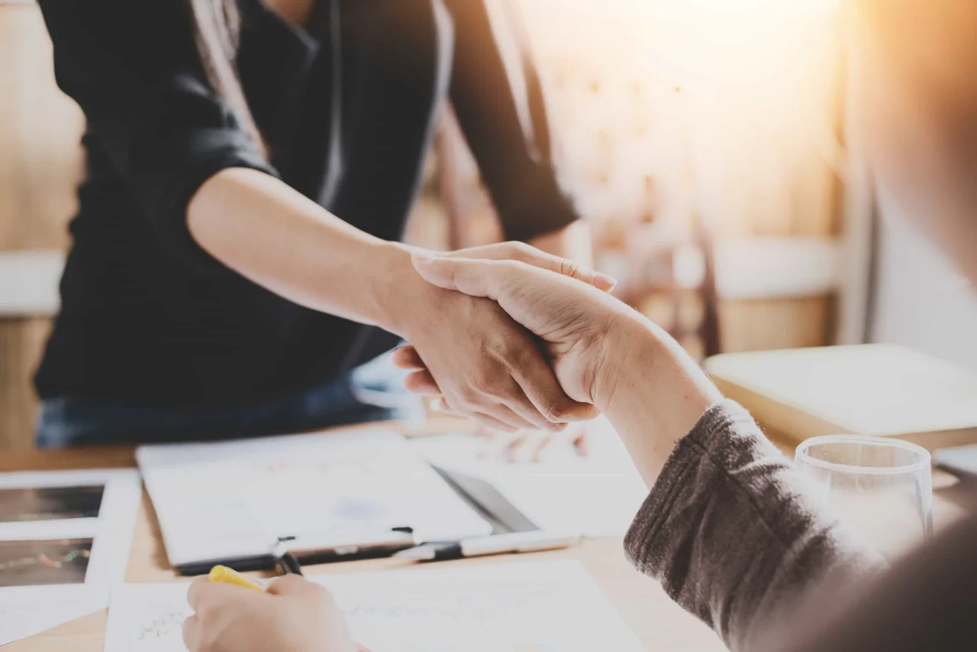 Close de duas pessoas de negócios apertando as mãos firmemente.
