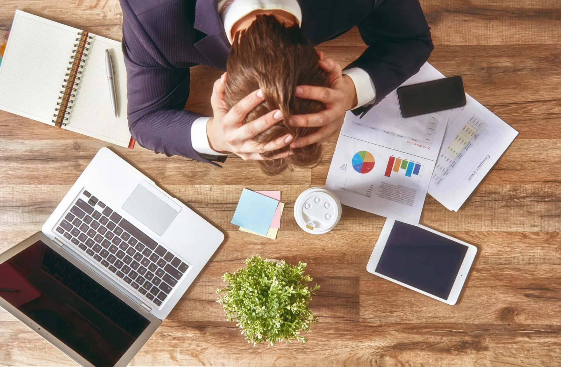 Homem estressado em sua mesa de trabalho, com a mão na cabeça.
