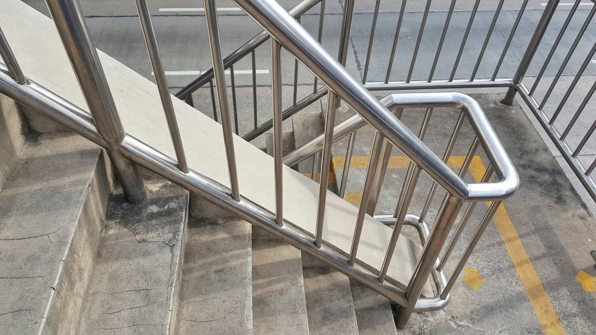 Mão de uma pessoa segurando firmemente um corrimão de metal em uma escada.
