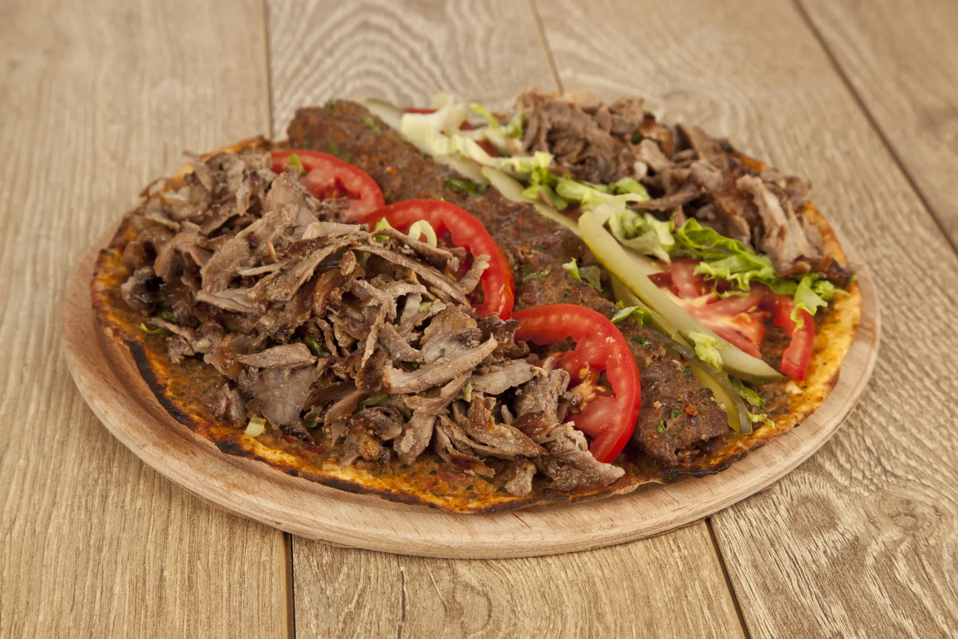Pizza coberta com carne de kebab, salada e molho de iogurte.