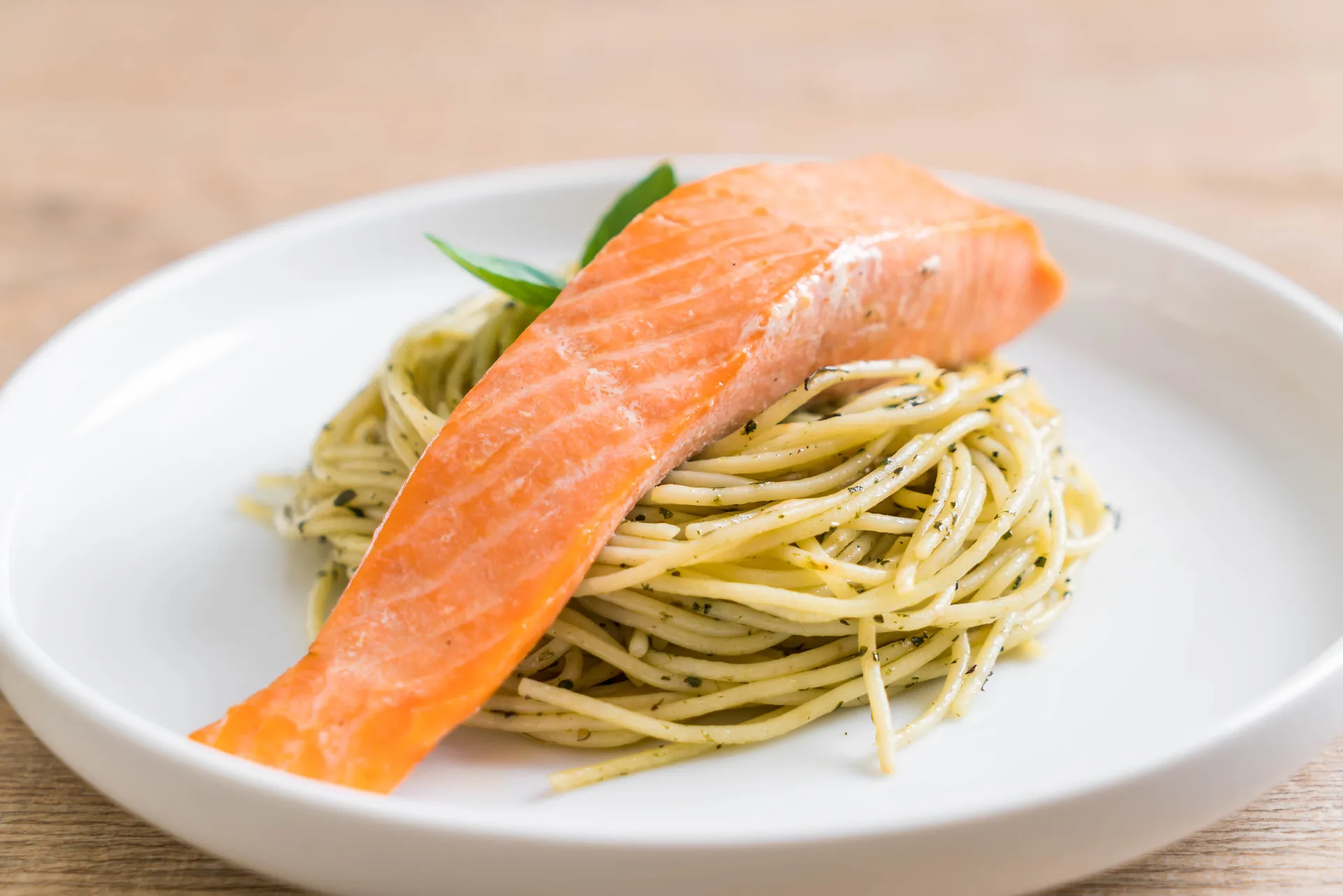 Prato de macarrão com molho pesto e pedaços de salmão.