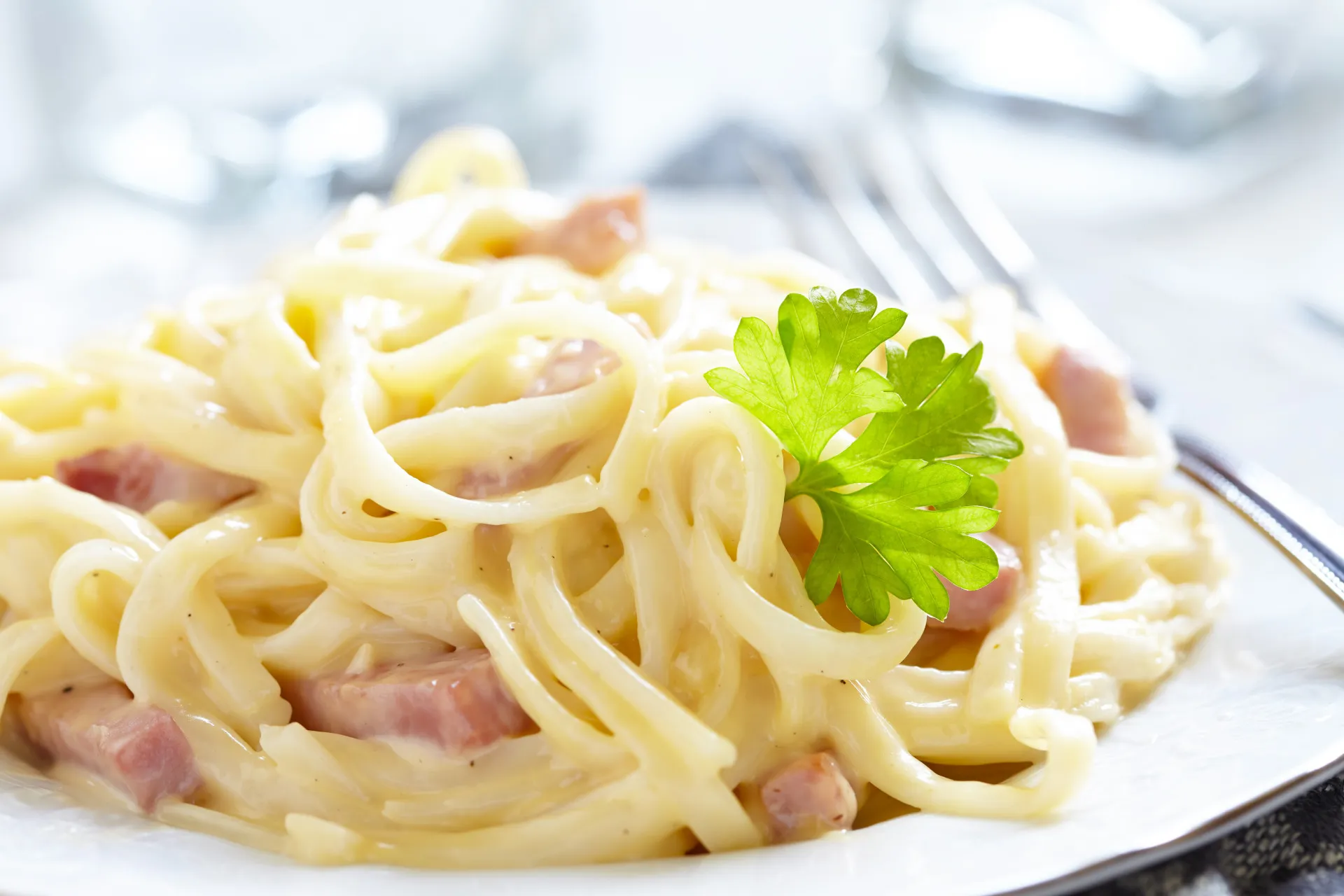 Prato de espaguete à carbonara com pedaços de bacon e queijo ralado.