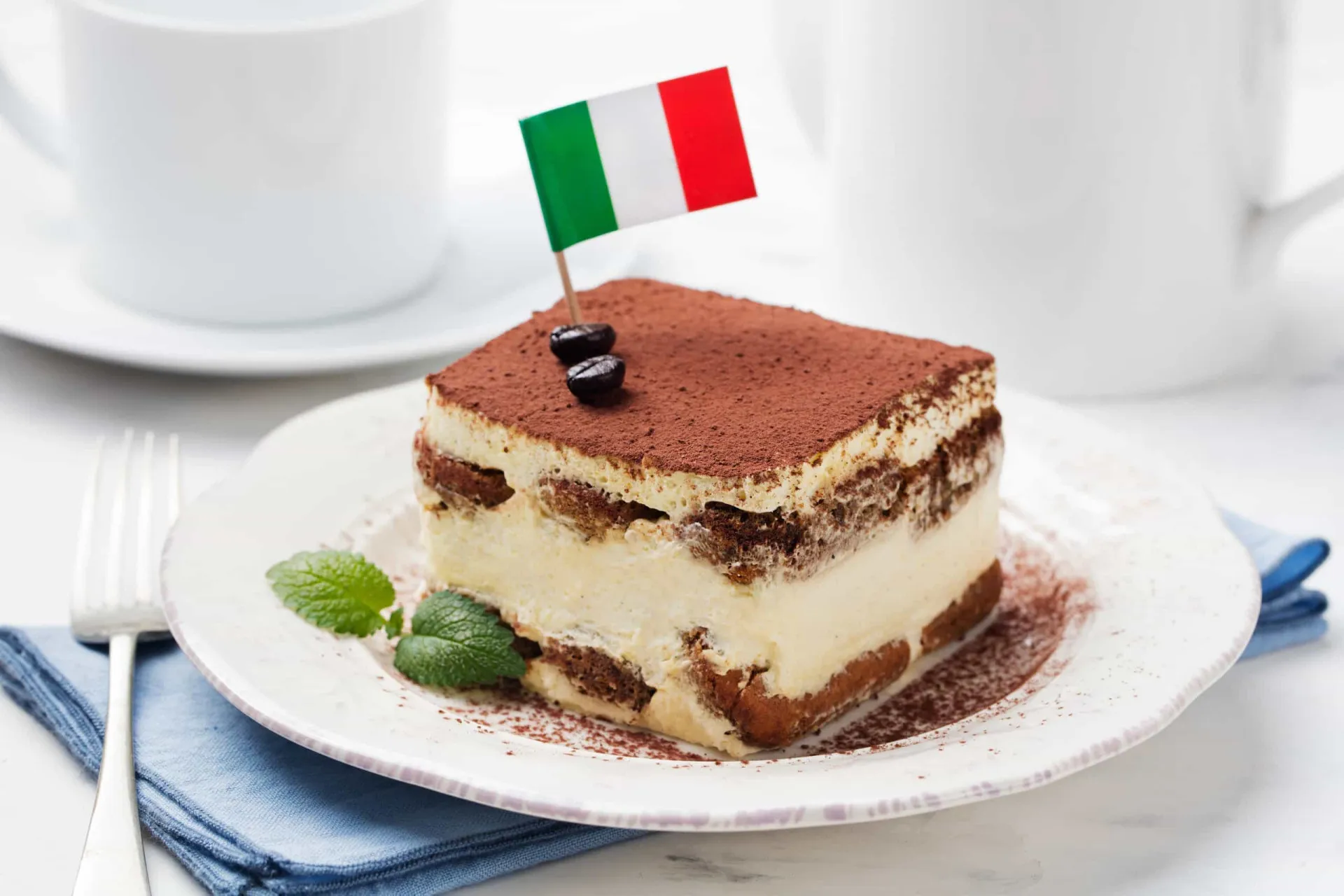 Pedaço de tiramisù em um prato, mostrando as camadas de creme e biscoito.