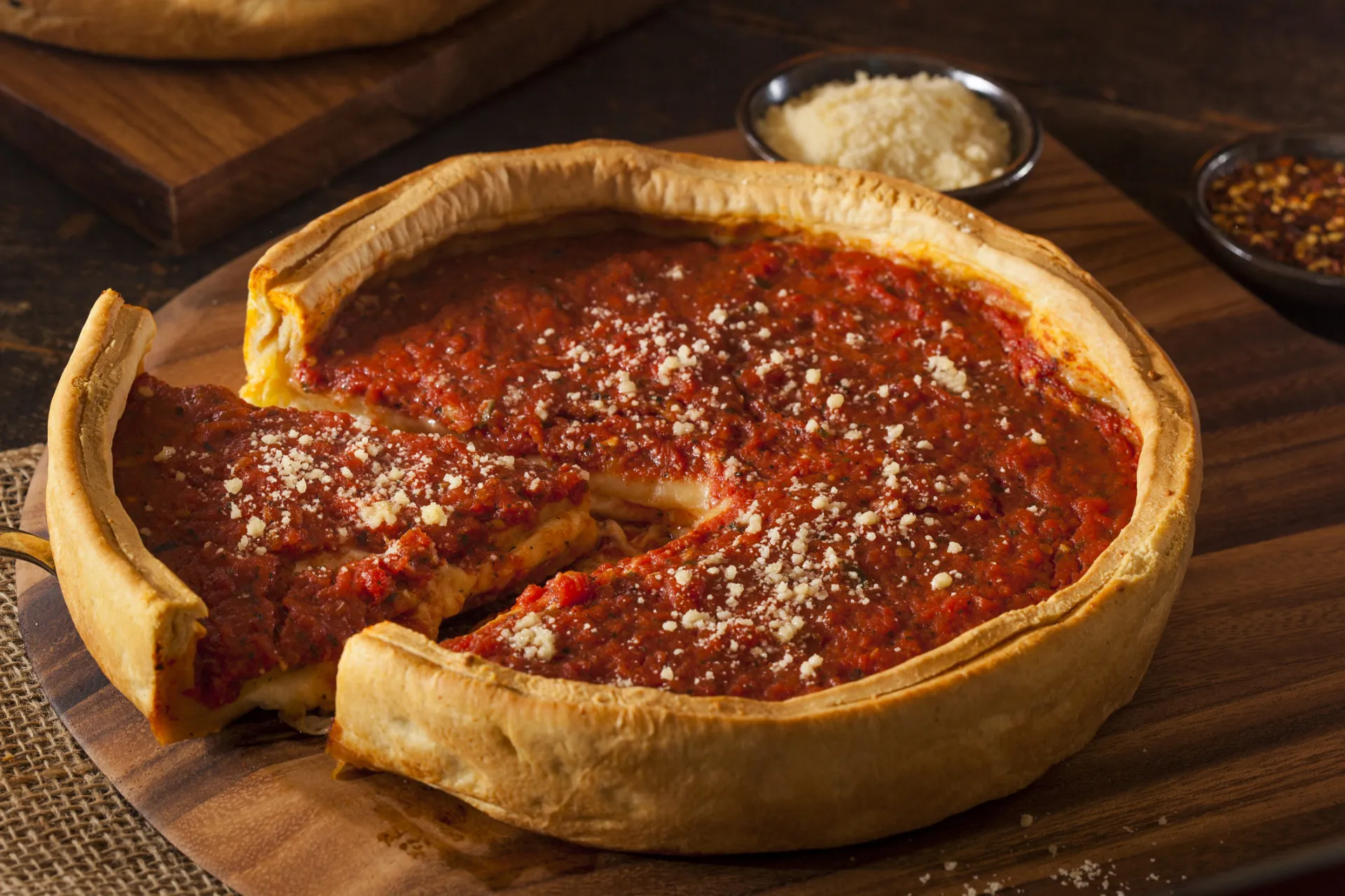 Fatia de pizza estilo Chicago, com massa grossa e alta, recheio profundo e muito queijo.