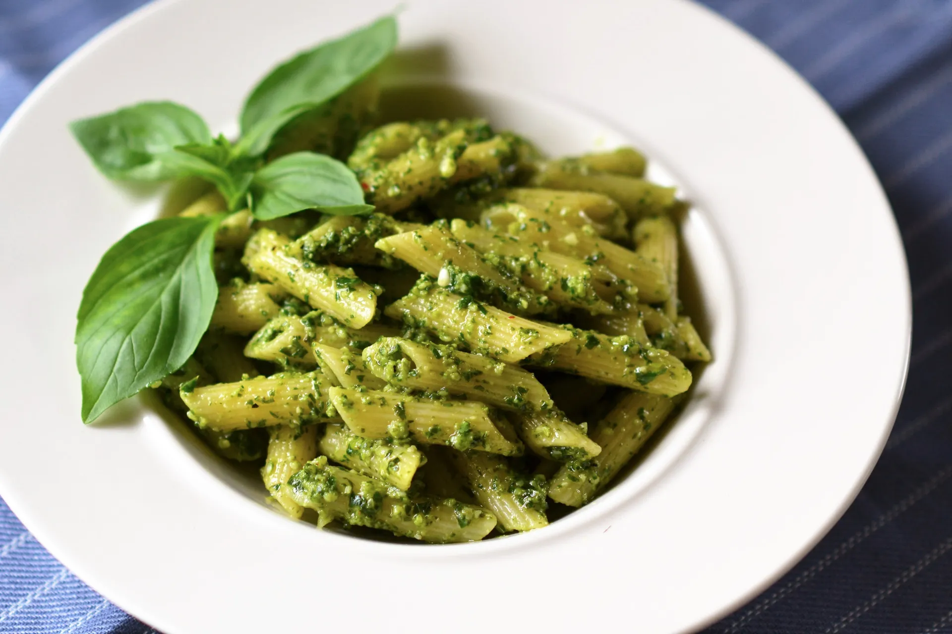 Pesto sendo preparado em um pilão com manjericão, queijo, alho e pinhões.