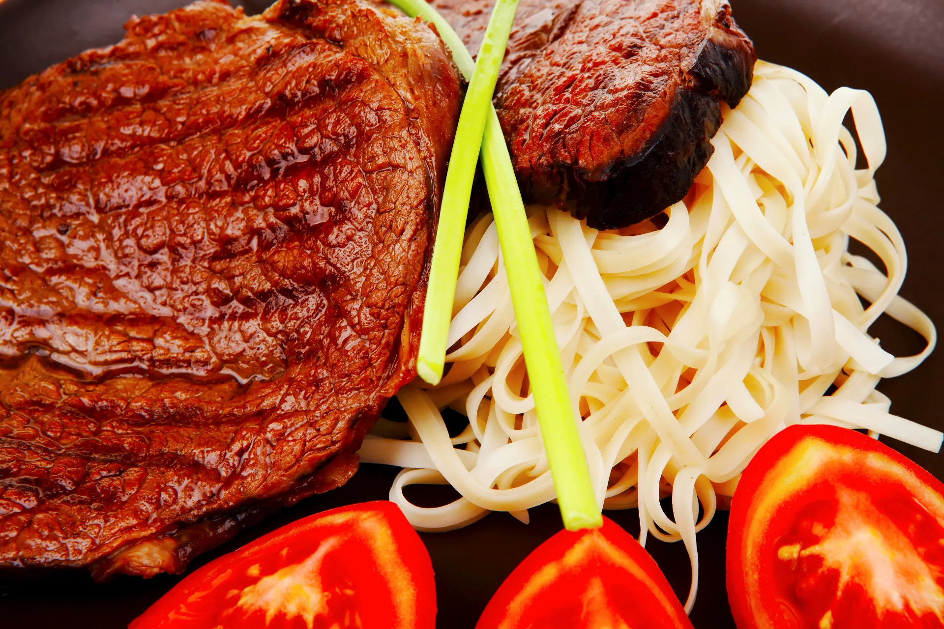 Prato de bife com uma pequena porção de macarrão ao lado como acompanhamento.