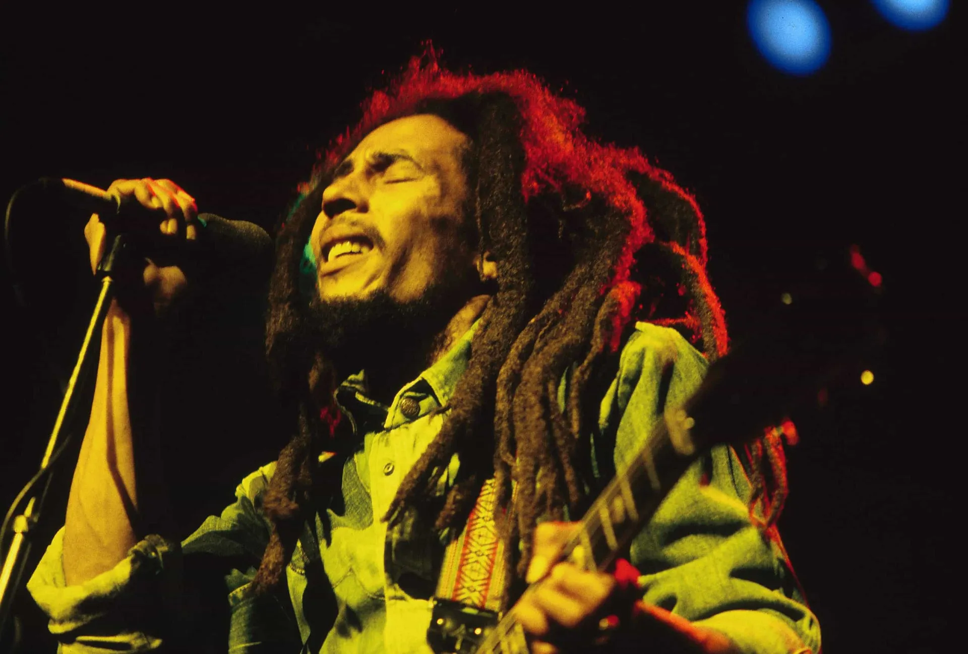 Bob Marley cantando em um show, com seus dreadlocks característicos e expressão apaixonada.