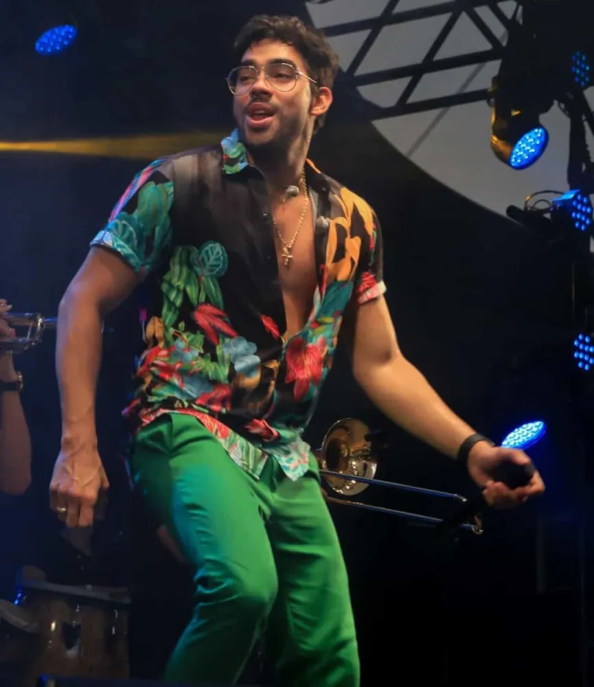 O cantor Gabriel Diniz sorrindo durante um show.