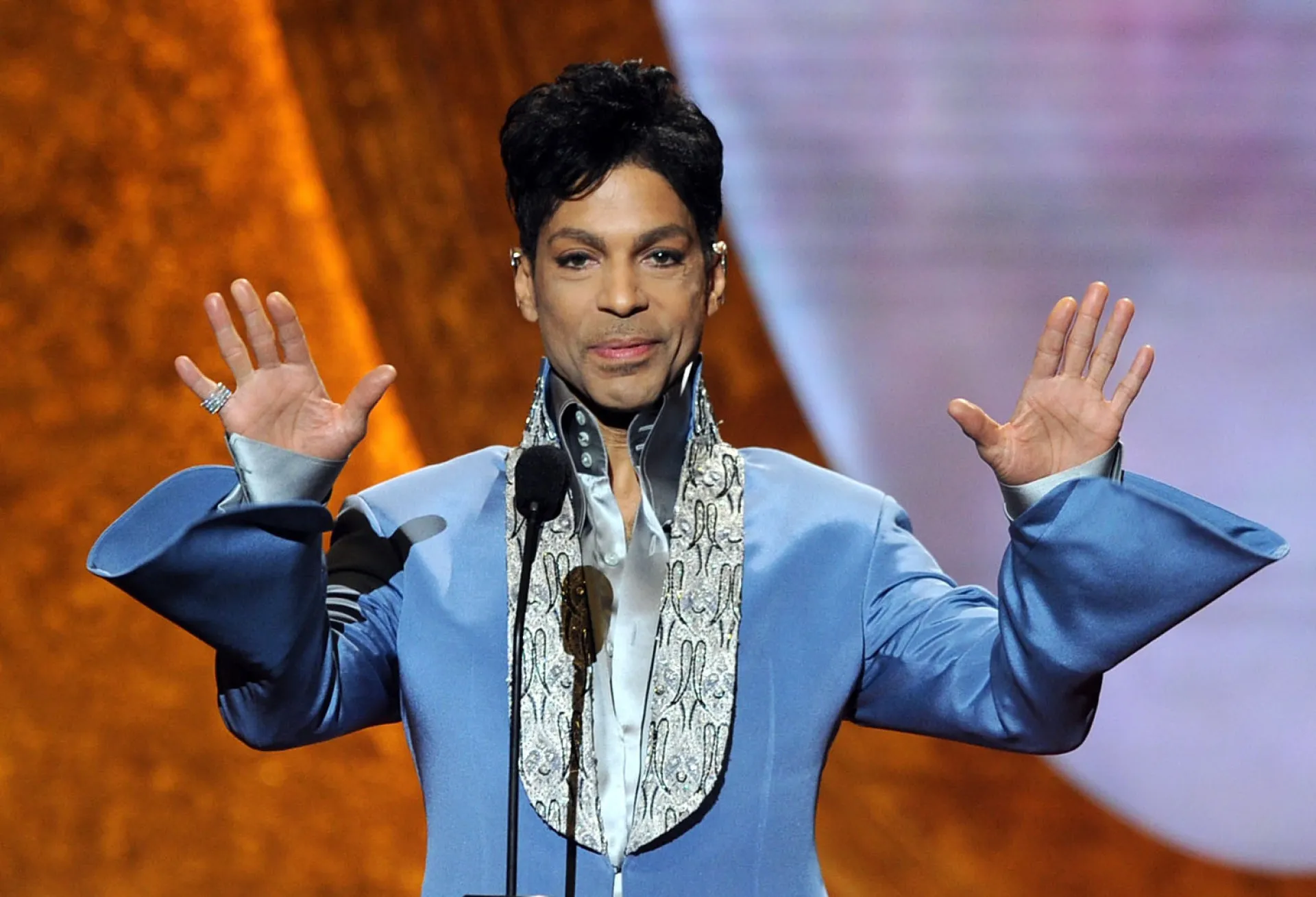 O músico Prince no palco, com sua guitarra roxa icônica.