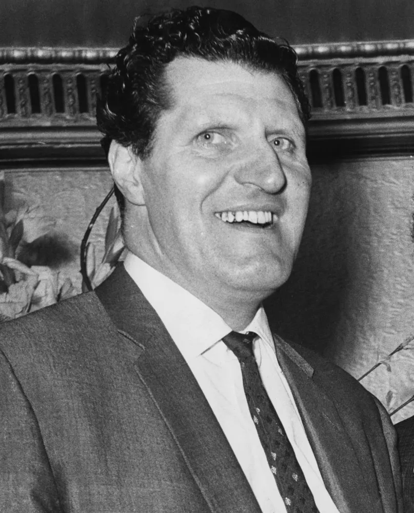 O comediante britânico Tommy Cooper usando seu famoso chapéu fez.