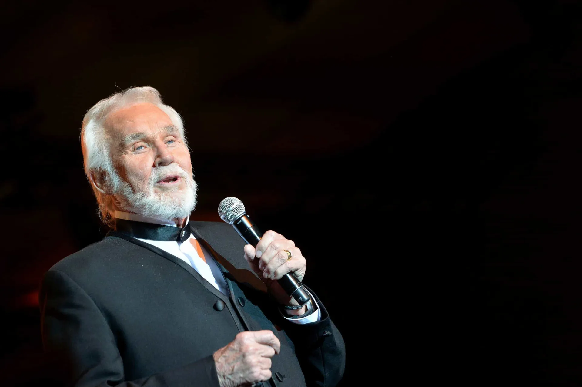 O cantor country Kenny Rogers com seu chapéu característico e barba branca.