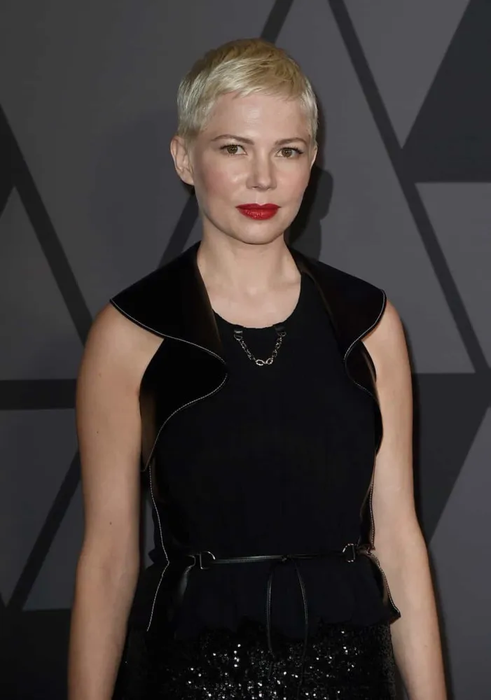 A atriz Michelle Williams com uma expressão introspectiva e delicada.