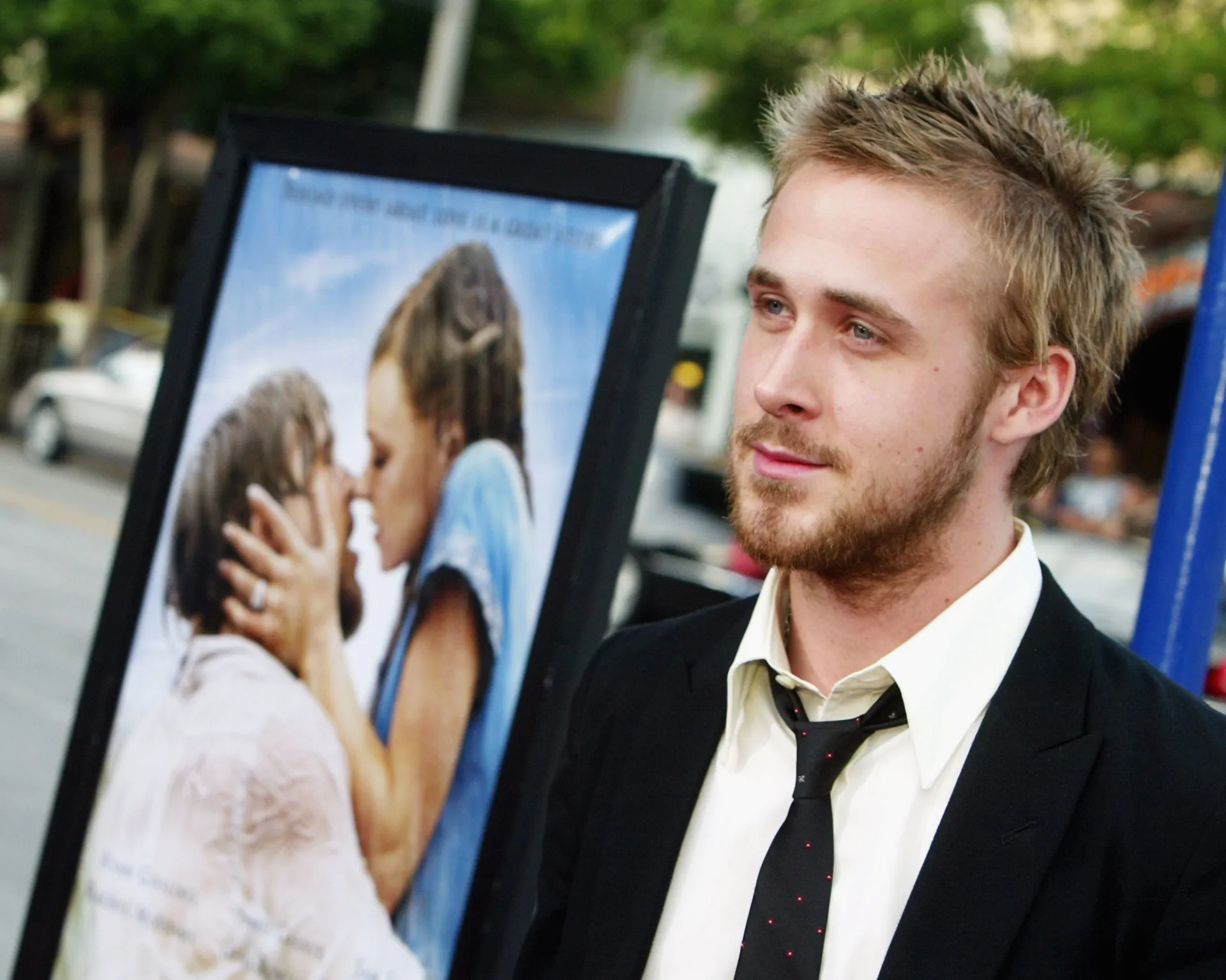 O ator Ryan Gosling com um sorriso charmoso em um tapete vermelho.