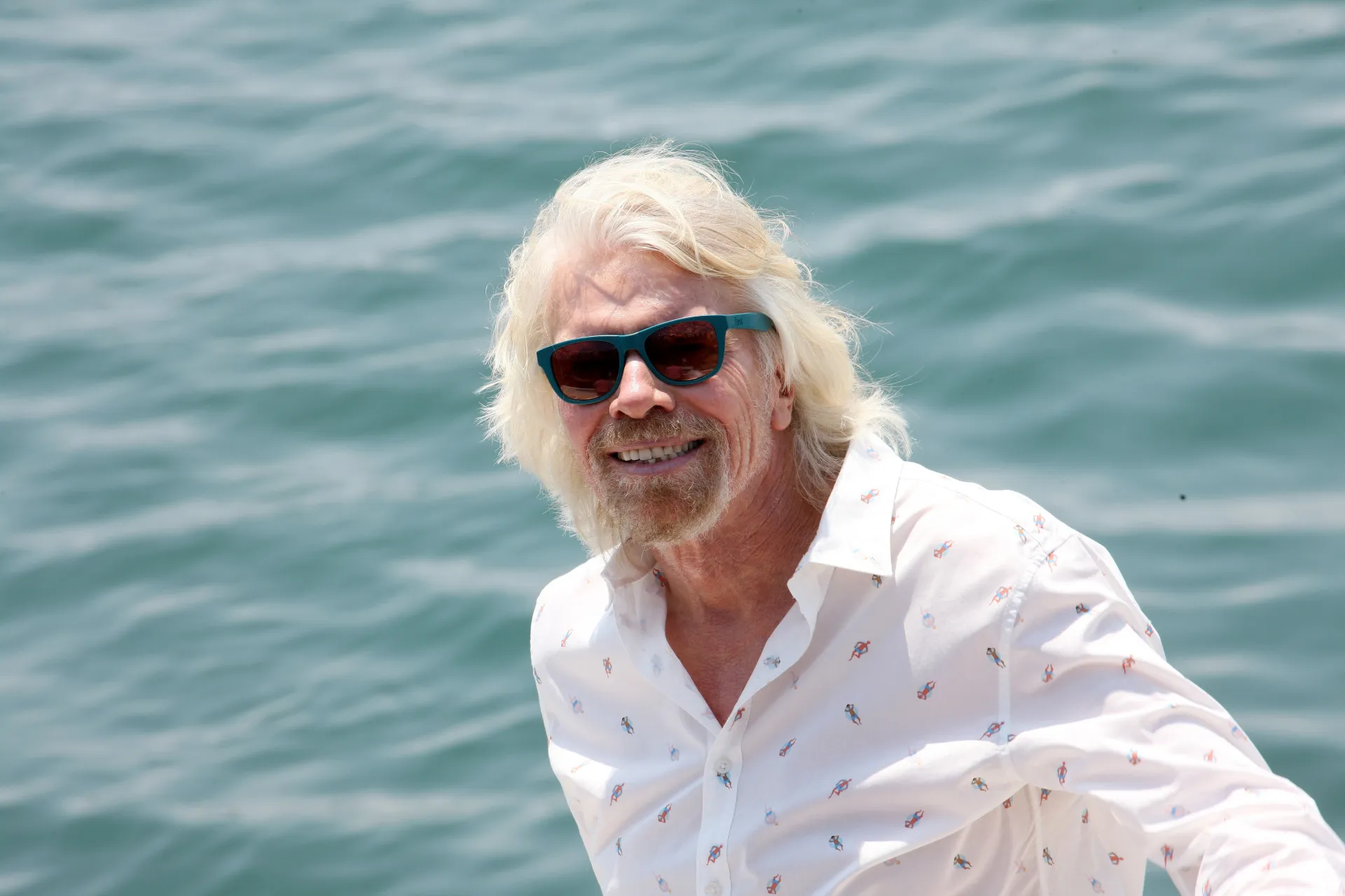 O magnata dos negócios Richard Branson com seu sorriso característico e cabelos longos.
