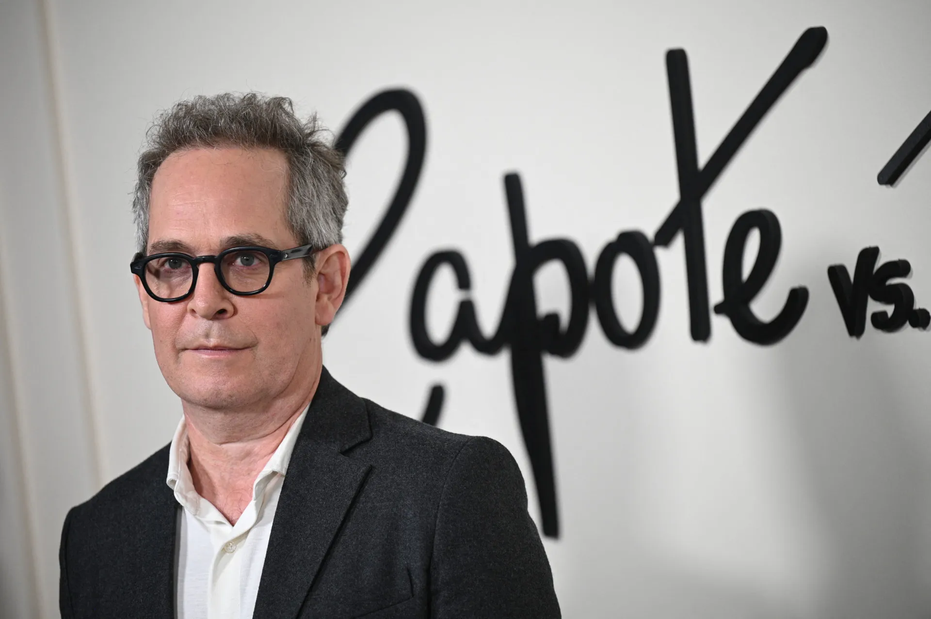 O ator Tom Hollander com um olhar pensativo durante uma entrevista.