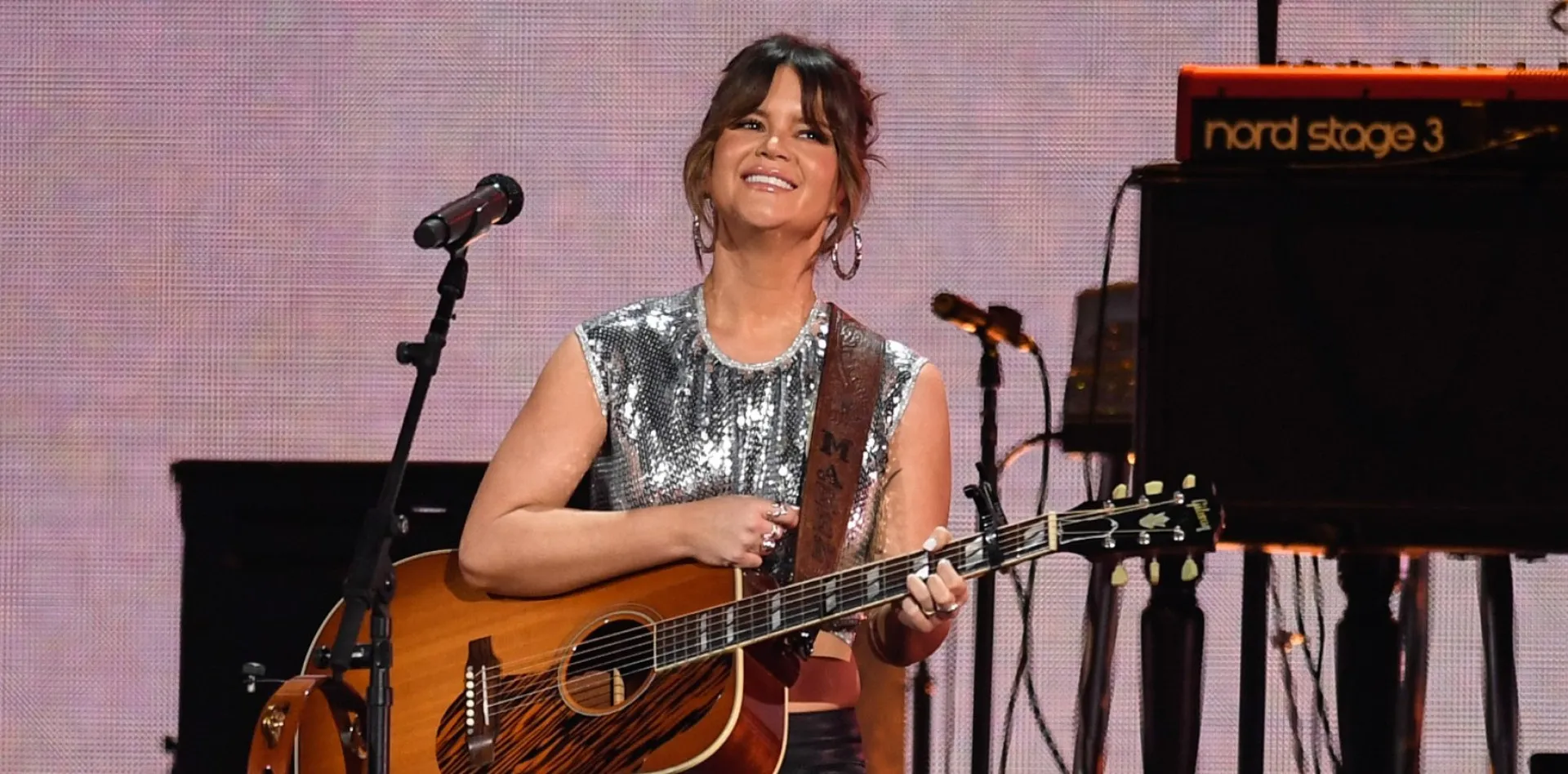 A cantora country Maren Morris se apresentando no palco com uma bandeira do orgulho.