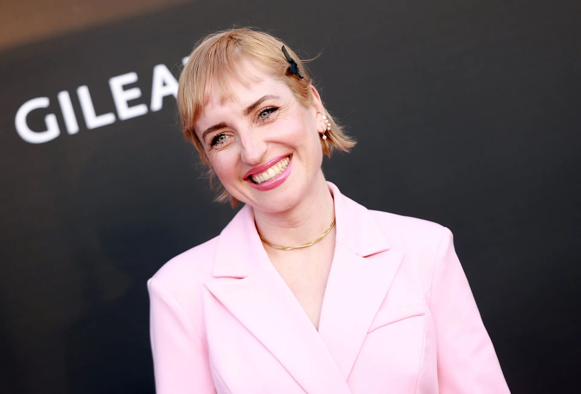 A atriz Zoe Lister-Jones em um evento de premiação, com um visual elegante.