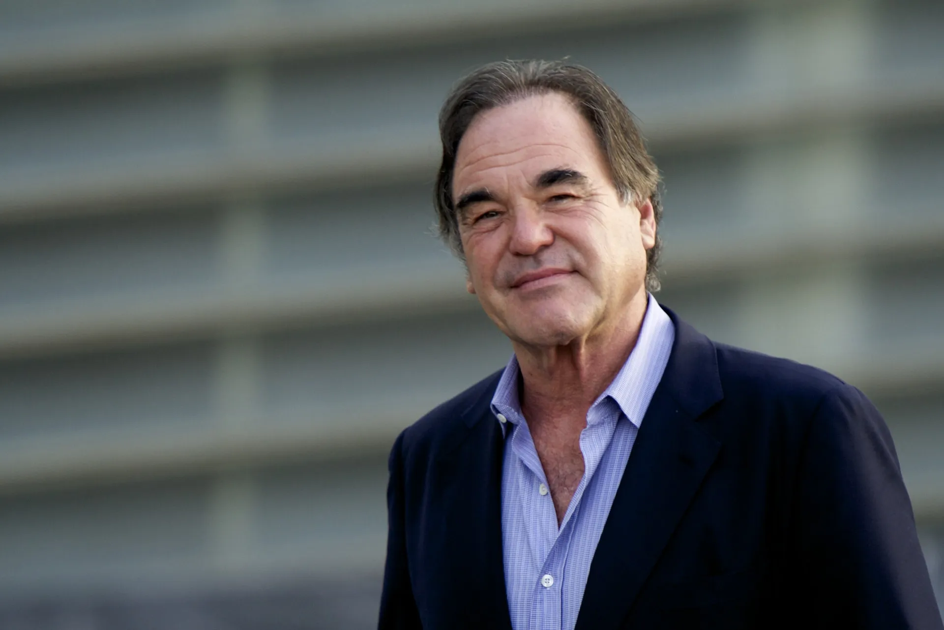 O diretor Oliver Stone em um evento, com um olhar pensativo e experiente.
