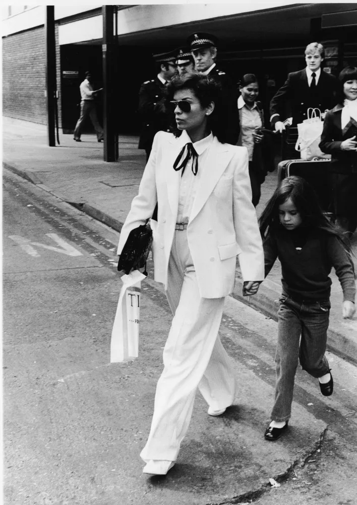 Bianca Jagger em seu casamento com Mick Jagger, usando um icônico terninho branco sem blusa por baixo.
