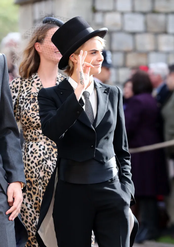 A modelo e atriz Cara Delevingne usando um smoking preto com cartola em um casamento real.