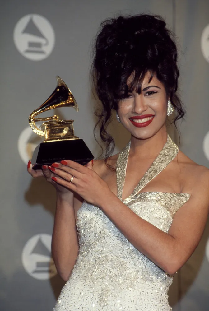 A cantora Selena Quintanilla sorrindo em uma foto de estúdio.