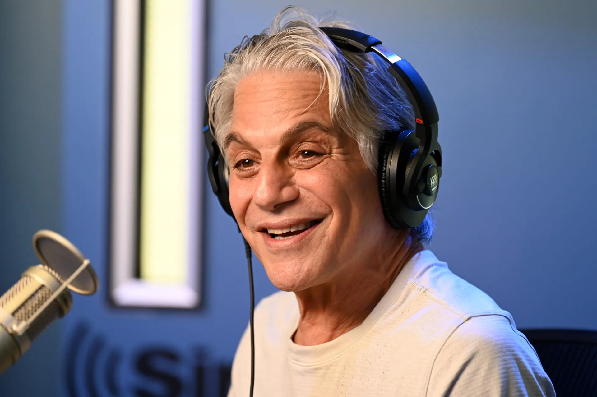O ator Tony Danza, protagonista de séries de sucesso, cantando em um palco.