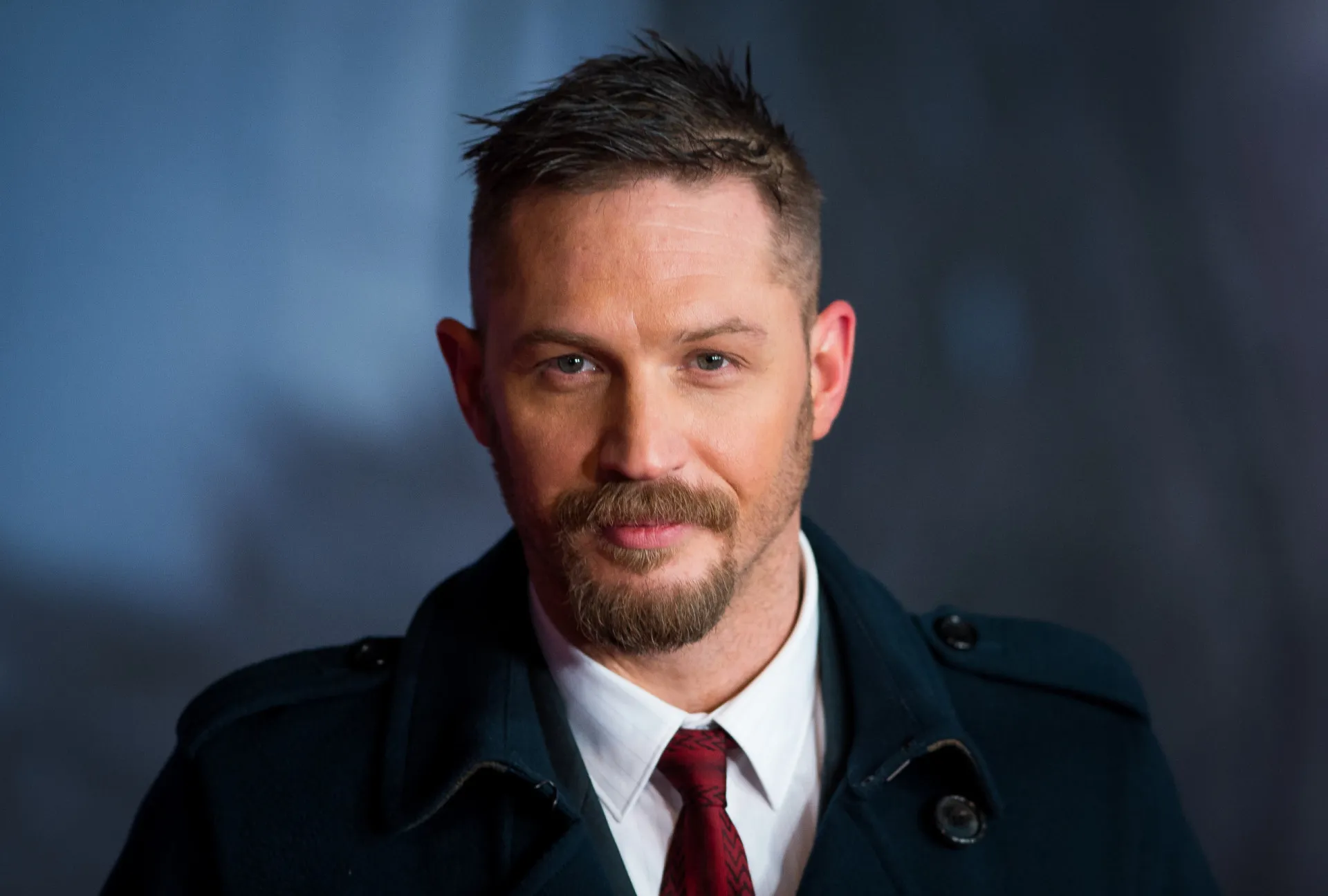 O ator Tom Hardy com um olhar sério em um evento de tapete vermelho.