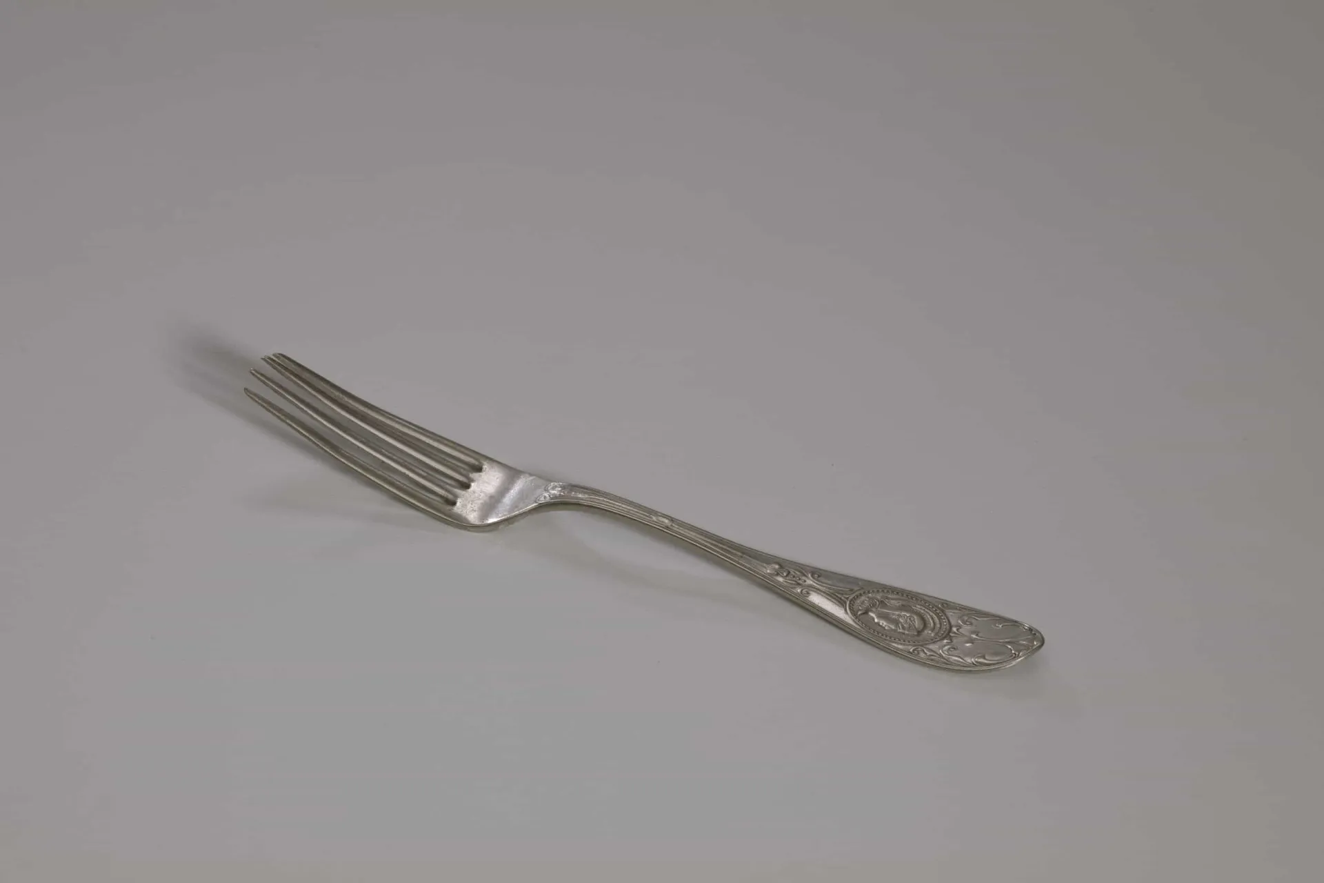 Um garfo de metal ornamentado sobre uma mesa de madeira rústica, simbolizando sua introdução histórica.