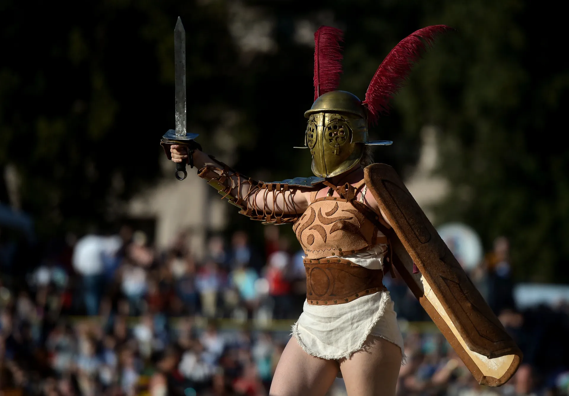 Reconstituição de duas mulheres gladiadoras lutando em uma arena romana, equipadas com espadas e escudos.