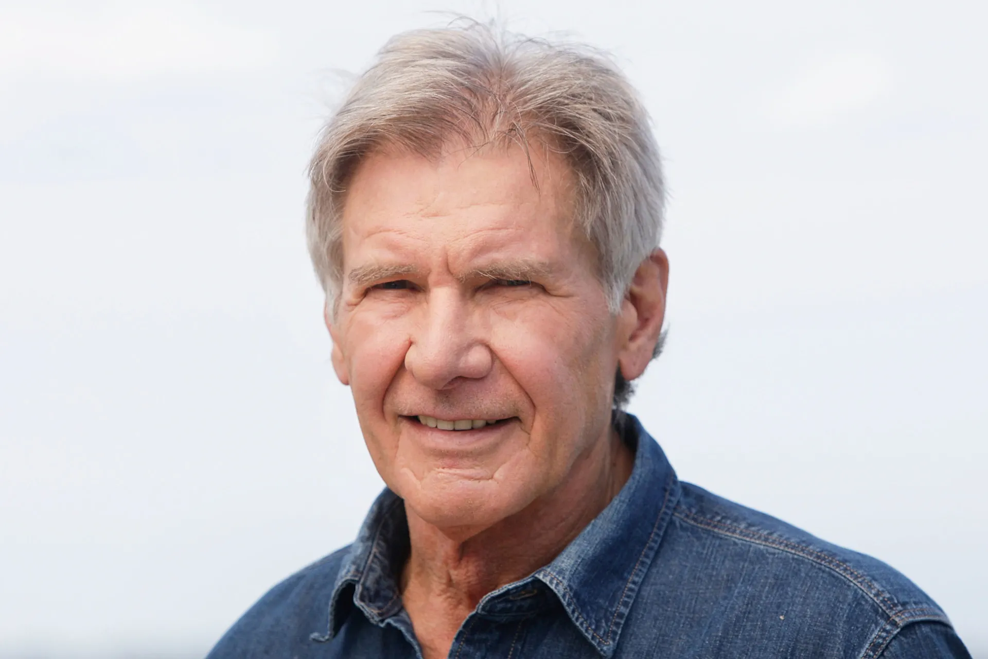 O ator Harrison Ford com seu sorriso característico e jaqueta de couro.