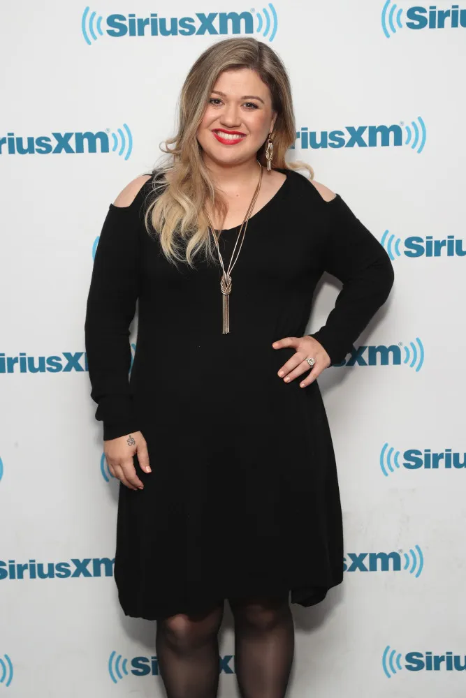 A cantora e apresentadora Kelly Clarkson sorrindo de forma espontânea.