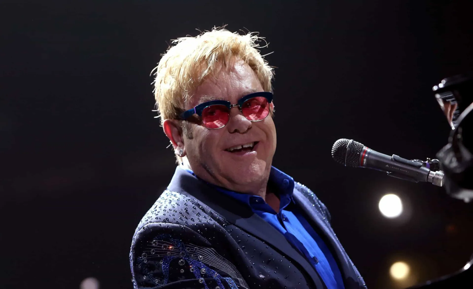 O cantor Elton John em uma de suas apresentações extravagantes no palco.